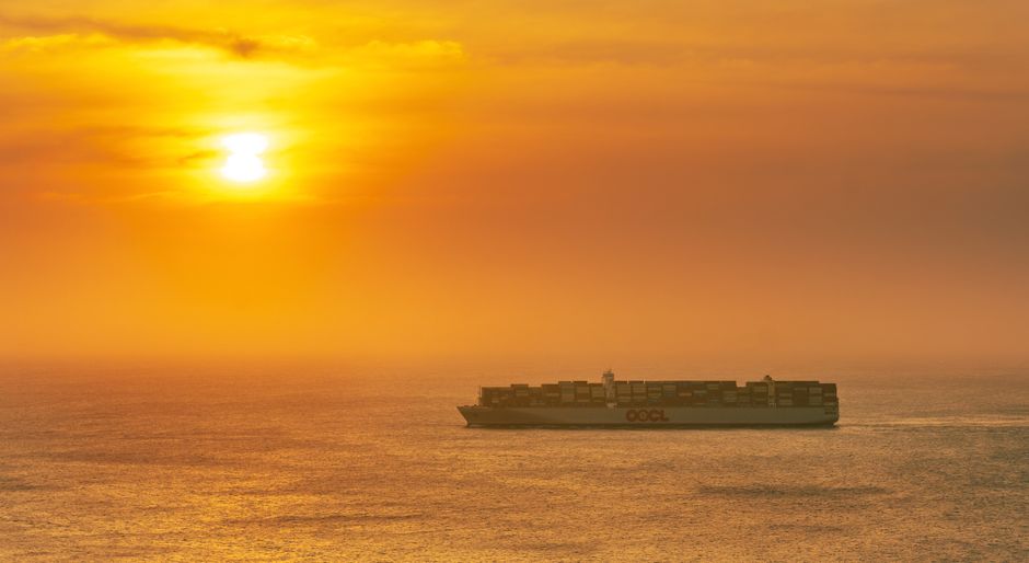 statek kontenerowy płynący przez spokojny ocean podczas zachodu słońca